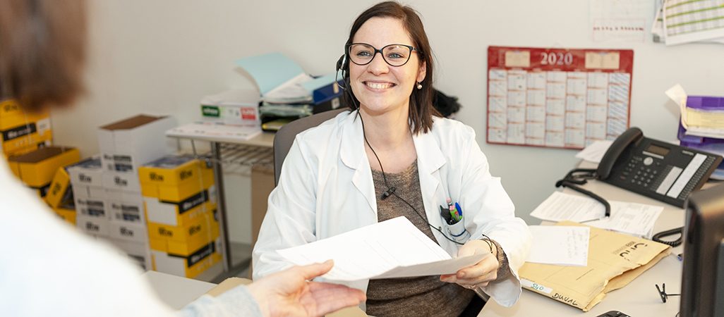une secrétaire en chirurgie-gynécologie-cancer_ donne un document à une patiente